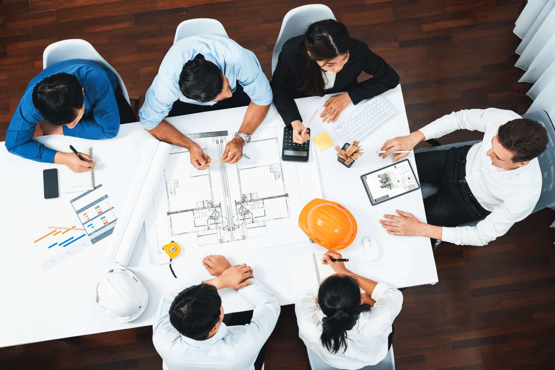 Top view banner of diverse group of civil engineer and client working together on architectural project, reviewing construction plan and building blueprint at meeting table. Prudent